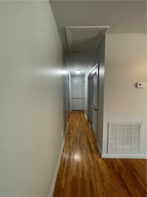 hallway featuring wood-type flooring and a textured ceiling