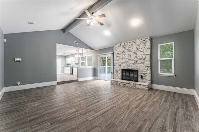 unfurnished living room featuring dark wood-type flooring, a stone fireplace, ceiling fan, and lofted ceiling with beams