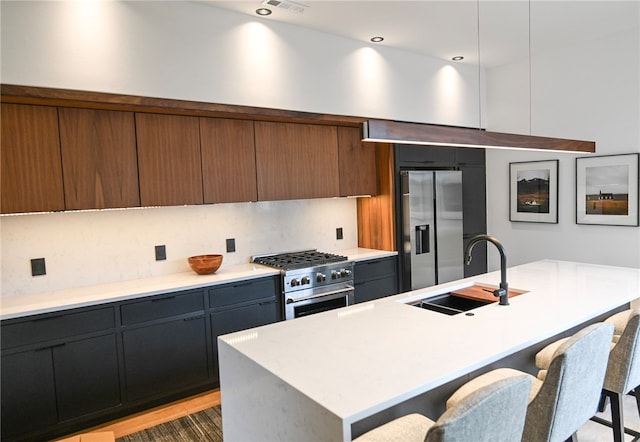 kitchen featuring tasteful backsplash, a center island with sink, stainless steel appliances, a kitchen bar, and sink