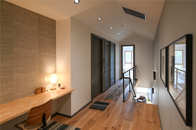 hallway featuring tile walls, vaulted ceiling, and light hardwood / wood-style flooring