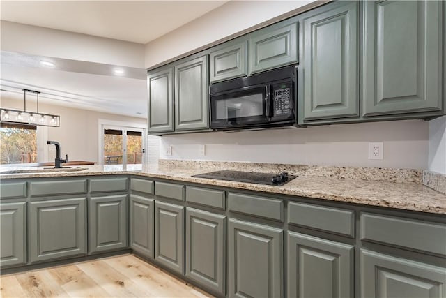 kitchen featuring light wood-style floors, black appliances, gray cabinetry, and light stone counters