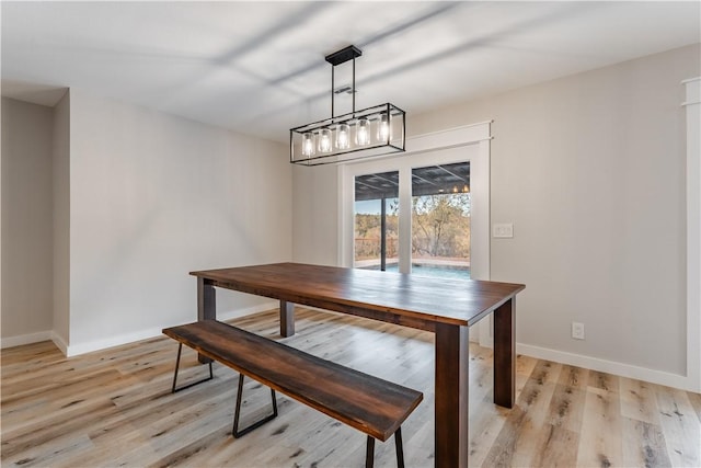 dining space featuring baseboards and light wood finished floors