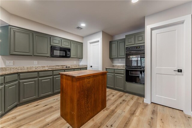 kitchen with light hardwood / wood-style floors, green cabinets, light stone countertops, and black appliances