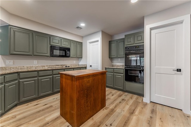 kitchen featuring visible vents, recessed lighting, light wood-type flooring, black appliances, and a center island