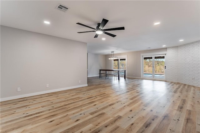 spare room with light wood-type flooring, baseboards, brick wall, visible vents, and a ceiling fan