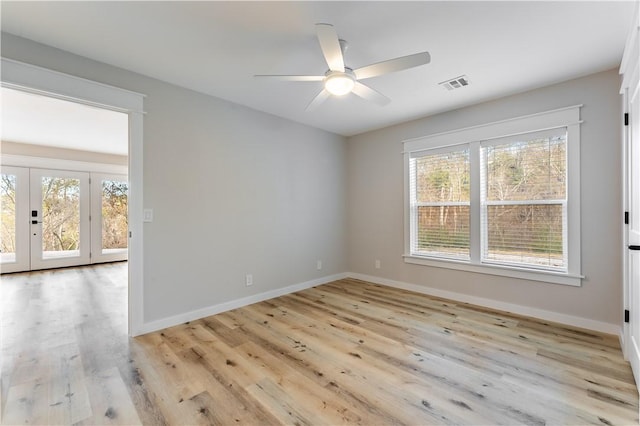 spare room with a ceiling fan, plenty of natural light, baseboards, and light wood finished floors