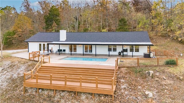10729 Anzac Dr, Lowell, AR 72745 - back of property featuring a chimney, an outdoor pool, central air condition unit, a shingled roof, and a patio