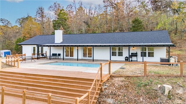 10729 Anzac Dr, Lowell, AR 72745 - rear view of property featuring a chimney, an outdoor pool, a shingled roof, a wooden deck, and cooling unit