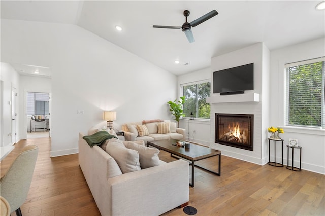 living room featuring a wealth of natural light, ceiling fan, light wood-type flooring, and vaulted ceiling