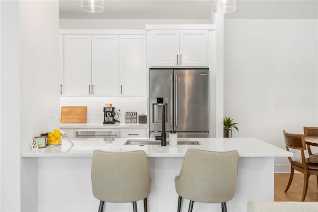 110 NE Briartown, Bentonville, AR 72712 - kitchen featuring high end refrigerator, white cabinets, backsplash, a breakfast bar, and pendant lighting