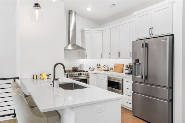 110 NE Briartown, Bentonville, AR 72712 - kitchen with a kitchen bar, high end appliances, white cabinets, wall chimney range hood, and decorative light fixtures