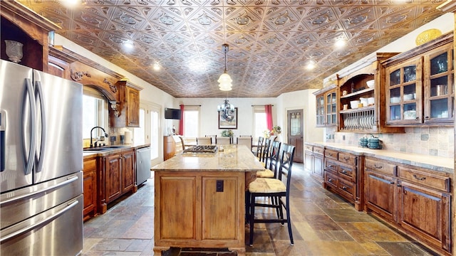 kitchen with stainless steel appliances, sink, a kitchen bar, decorative light fixtures, and a center island