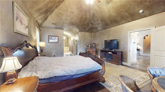 bedroom featuring ensuite bath and vaulted ceiling