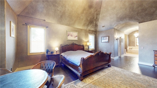 bedroom featuring hardwood / wood-style floors, ensuite bathroom, and lofted ceiling