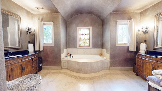 bathroom with tile patterned flooring, vanity, lofted ceiling, and a relaxing tiled tub