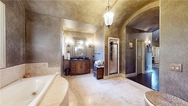 bathroom featuring vanity, hardwood / wood-style flooring, lofted ceiling, and plus walk in shower