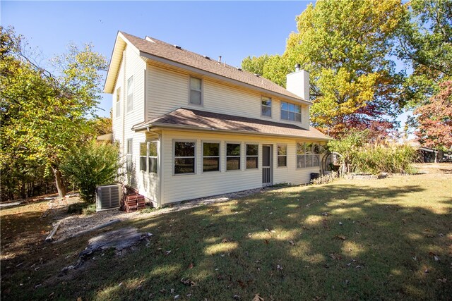 rear view of property featuring a yard and cooling unit