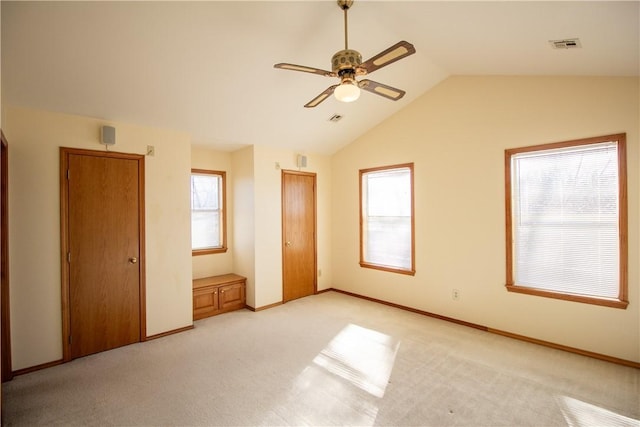 unfurnished bedroom featuring ceiling fan, light carpet, and multiple windows