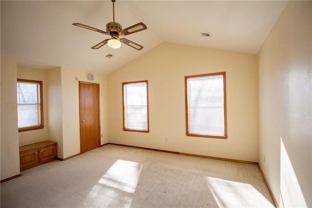 unfurnished bedroom featuring ceiling fan, light colored carpet, vaulted ceiling, and multiple windows