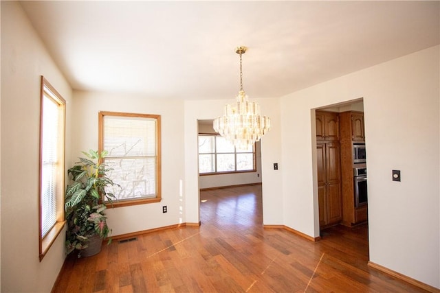 unfurnished dining area with hardwood / wood-style flooring and a chandelier