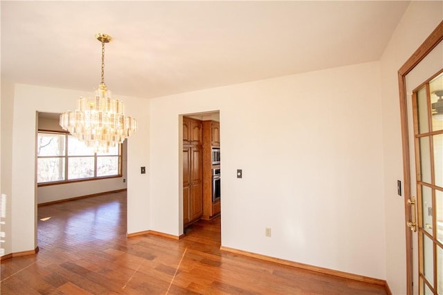 spare room with a chandelier and light hardwood / wood-style floors