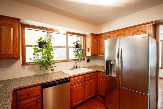 kitchen with sink, tasteful backsplash, light stone countertops, dark hardwood / wood-style floors, and stainless steel appliances