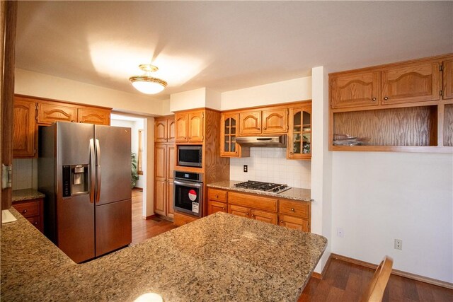 kitchen with light stone counters, dark hardwood / wood-style flooring, tasteful backsplash, and stainless steel appliances