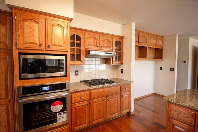 kitchen featuring light stone counters, dark hardwood / wood-style floors, stainless steel appliances, and tasteful backsplash