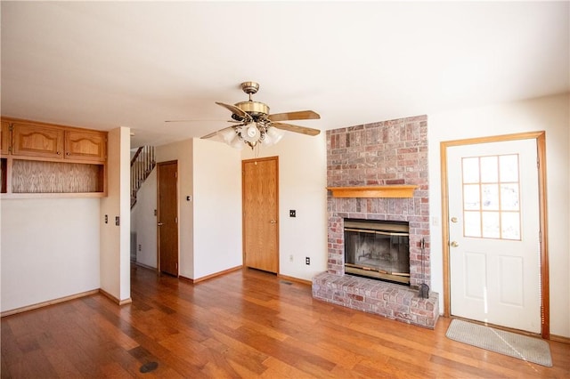 unfurnished living room with ceiling fan, hardwood / wood-style floors, and a brick fireplace