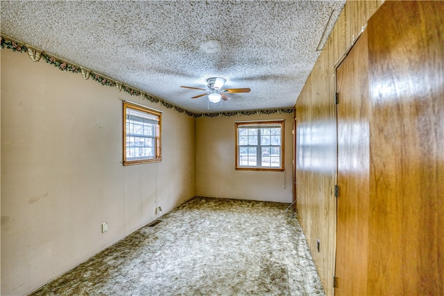 spare room featuring carpet, a textured ceiling, and ceiling fan