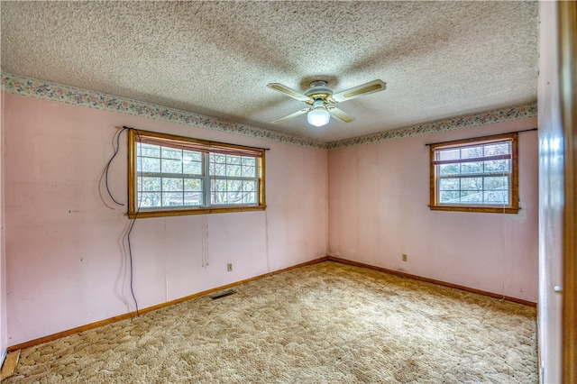 empty room with a textured ceiling, light colored carpet, and ceiling fan