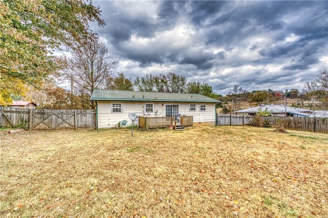 rear view of house featuring a lawn and a deck