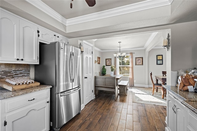 kitchen featuring white cabinetry, ornamental molding, hanging light fixtures, stainless steel fridge, and dark hardwood / wood-style flooring