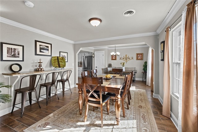 dining space featuring dark wood-type flooring, a notable chandelier, and ornamental molding