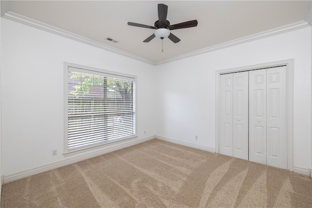 unfurnished bedroom with ornamental molding, a closet, carpet, and ceiling fan