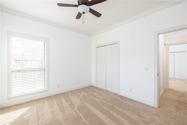 unfurnished bedroom featuring ceiling fan, light carpet, a closet, and crown molding