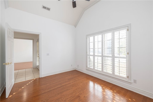 empty room featuring hardwood / wood-style floors, a wealth of natural light, ceiling fan, and high vaulted ceiling