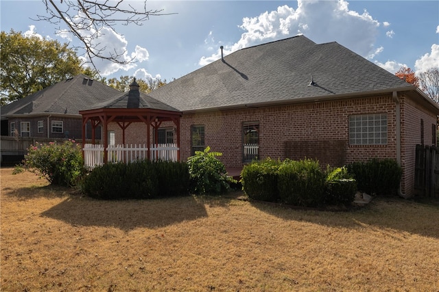 rear view of property featuring a lawn and a gazebo