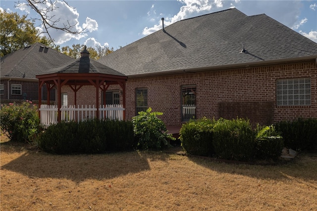 back of property with a yard and a gazebo