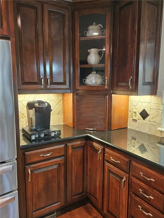 kitchen with stainless steel fridge, backsplash, dark hardwood / wood-style flooring, and dark brown cabinetry