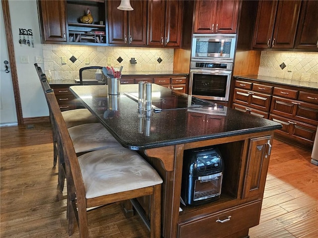 kitchen featuring a center island with sink, a breakfast bar area, appliances with stainless steel finishes, and tasteful backsplash