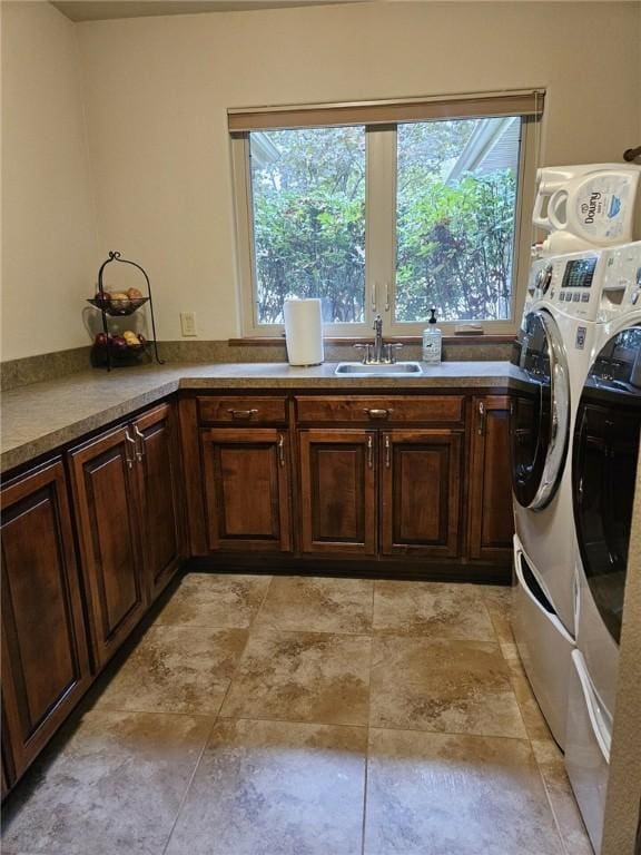 laundry room featuring washing machine and dryer, a wealth of natural light, sink, and cabinets