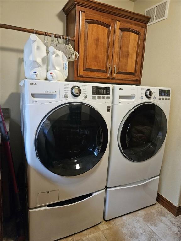 washroom with cabinets and washer and clothes dryer