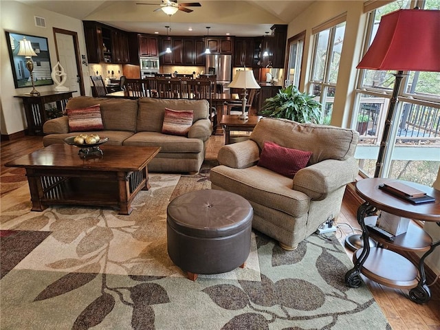 living room featuring vaulted ceiling, light hardwood / wood-style flooring, and ceiling fan