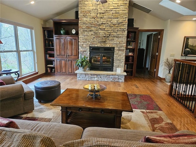 living room with a fireplace, light hardwood / wood-style floors, and vaulted ceiling