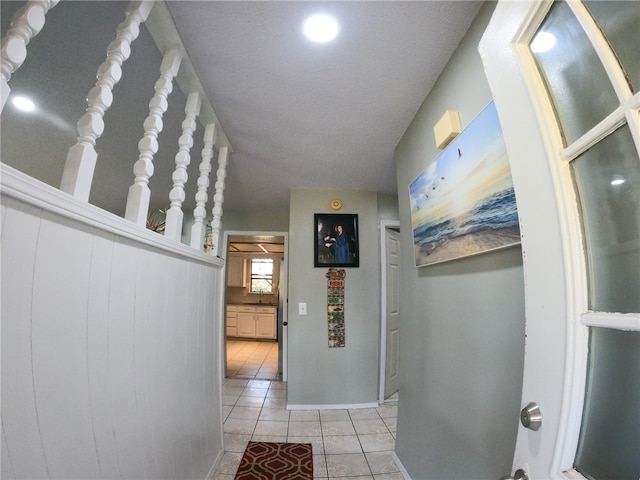 hallway with sink, light tile patterned floors, and a textured ceiling