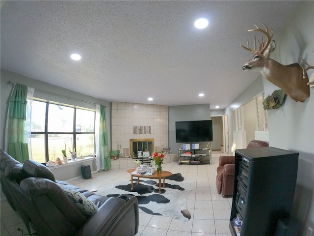 living room with a tiled fireplace, a textured ceiling, and light tile patterned floors