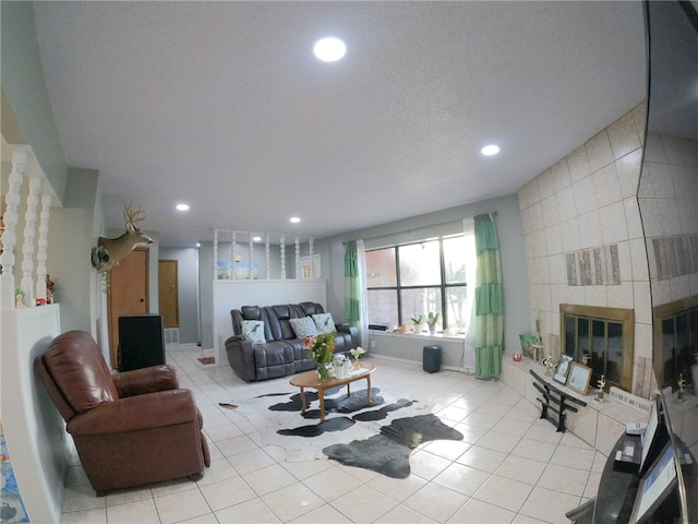 living room featuring a textured ceiling, light tile patterned flooring, and a fireplace