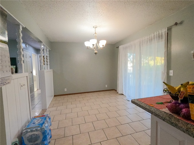 tiled dining area with a chandelier and a textured ceiling