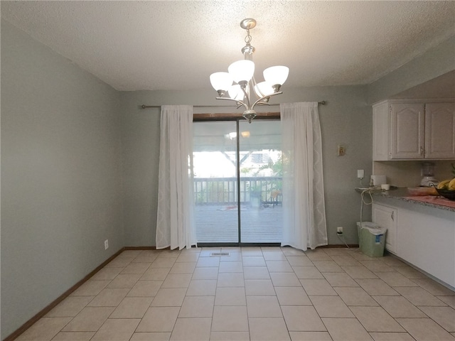 unfurnished dining area featuring a textured ceiling, light tile patterned floors, and a notable chandelier